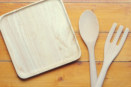 top view image of wooden spoon, fork and blank tray placed on wooden table, Different wooden kitchen tools on the table with copy spaceの写真素材