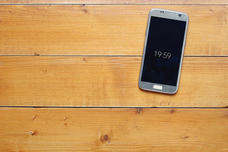Top view with copy space. smartphone with digital clock's on wooden desk, ready for adding text or...