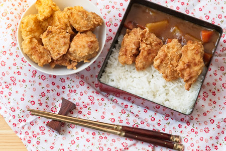 Top view Japanese curry rice topping with fried chicken and vegetables in black plate with...