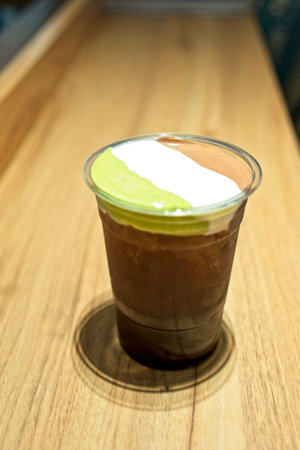 A plastic glass of iced tea with layer of cream cheese foam, Trendy food and drinks, Cheese Tea with...