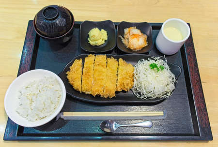 Japanese cuisine, pork deep fried cutlet Japanese food famous, Tonkatsu. Tonkatsu served with rice, miso soup, Chawanmushi and salad consists of fresh cabbages placed on wooden table. Top viewの写真素材