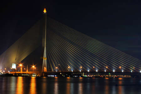 Asymmetric suspension bridge over the river at nightの写真素材