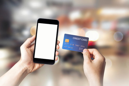 Hands holding credit card with Smart mobile phone show white screen background for your design...