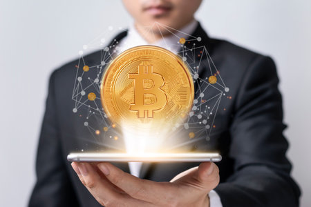 Asian businessmen hold a smartphone showing the world of virtual bitcoin trading on white background. Cryptocurrency and technology financial systems concept.の写真素材