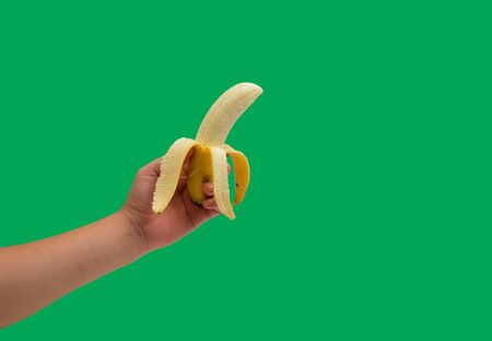 isolated hand holding banana on green backgroundの写真素材