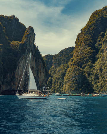 sail boat in lagoon surrounded by beautiful green mountain landscapeの写真素材