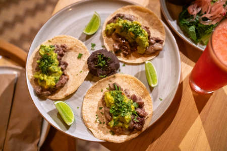 tasty steak tacos with beans, guacamole, cilantro, onions, and lime at a mexican restaurantの写真素材