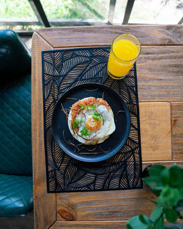 colombian arepa with an egg on top with orange juice at restaurantの写真素材