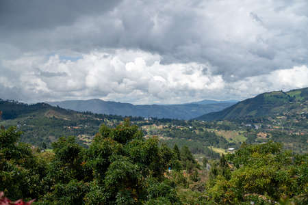 cloudy green landscape filled with mountains and nature during summerの写真素材