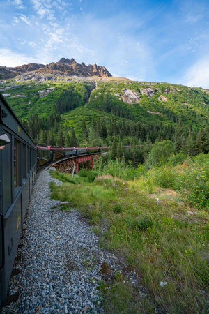 green landscape with train traveling in the mountains in alaskaの写真素材