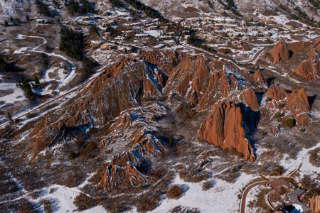close up of red rocks in colorado showing neighborhood in background covered in snow with large red mountains in foregroundの写真素材