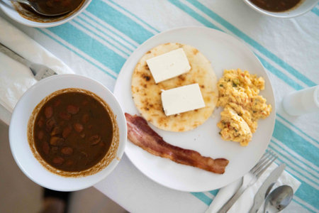 colombian breakfast with beans, bacon, eggs, arepa, and cheese in the morningの写真素材