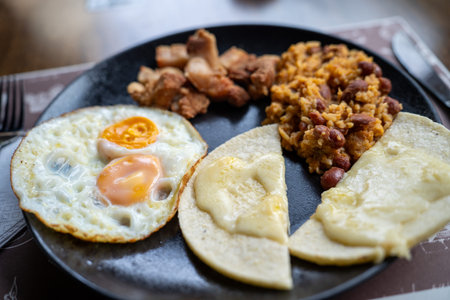 close up of corn arepa with melted cheese along with two fried eggs sunny side up for breakfast at colombian restaurantの写真素材