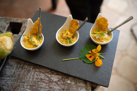 three yellow fish ceviche samplers with various vegetable seasoning, flower garnishes, and fried...