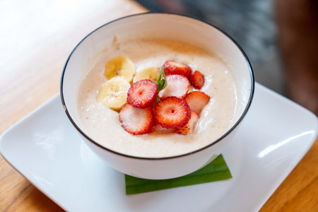 healthy and organic bowl of oatmeal with colorful and fresh strawberries and bananasの写真素材