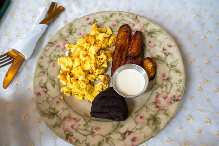 delicious meal at breakfast restaurant with eggs plantains beans and sauceの写真素材