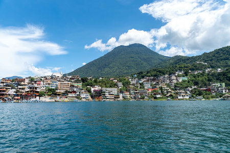 nature landscape during cloudy and sunny day at a lake with buildings and mountains in foreground with a lagoon from a boatの写真素材
