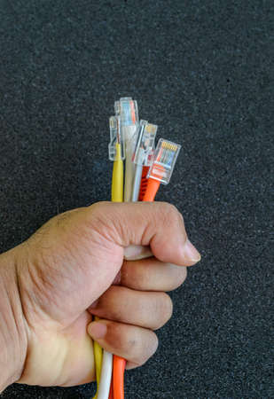 Hand holding colorful internet cables with black backgroundの写真素材