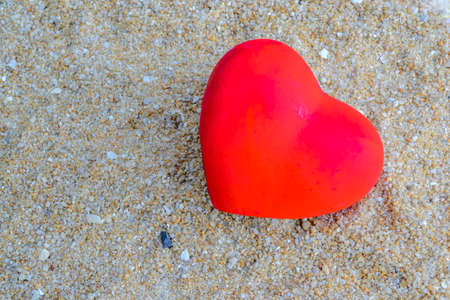 Ceramic red heart on sand backgroundの写真素材