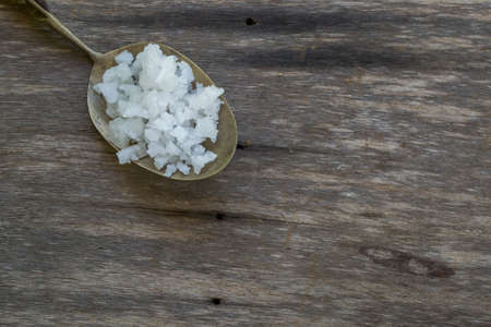salt in a brass spoon on wood backgroundの写真素材