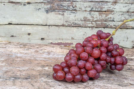 Bunch of red grapes on old wooden background.の写真素材