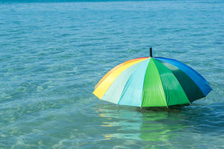 Closeup of colorful umbrella on sea waterの写真素材