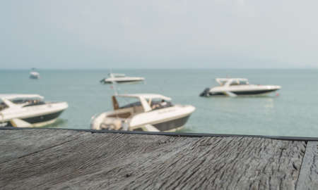 The old wood table with view of beach and speed boat blur background - for present object or productの写真素材
