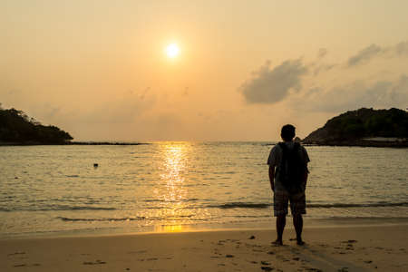 Young tourists stand and watch the sunrise in the morning at Choeng Mon Beach Koh Samui in Thailand.の写真素材