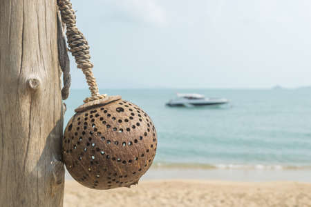 Lamp made from coconut shells with boat and beach blur background.の写真素材