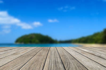 Wood table top with blurred nature scene tropical beach and blue sky backgroundの写真素材