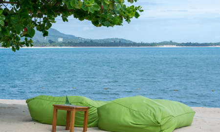 Two green bean bags on the beach under tree with blue sky backgroundのeditorial素材
