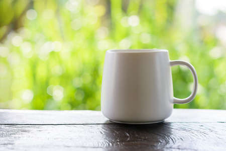 cup of coffee on table in cafe with Natural outdoors bokeh backgroundの写真素材