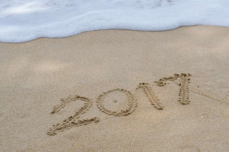 Year 2017 written at the sand beach with sea wave waterの写真素材