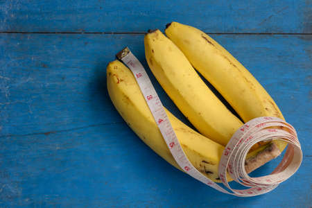 Bananas with a measuring cables on wooden background for Healthy concept.の写真素材