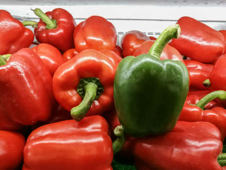 Only one green sweet pepper and Red Sweet peppers on the shelves in supermarketsの写真素材