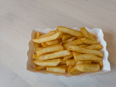 French fries in a paper box on wooden table backgroundの写真素材