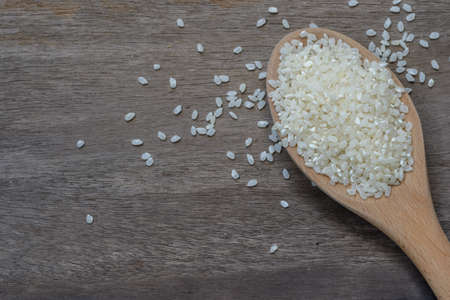 Japanese rice in wooden spoon on the old wood backgroundの写真素材