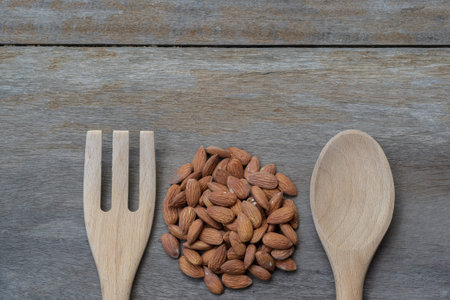 almond with wooden spoon and fork on the old wood backgroundの写真素材
