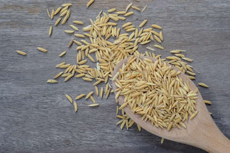 paddy rice seed in wooden spoon on the old wood backgroundの写真素材
