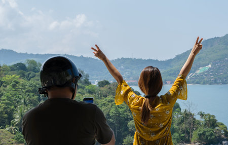 Travel couples are taking pictures with sea views by smart phone in Phuket Island,Thailandの写真素材