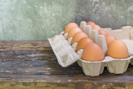 raw chicken eggs in egg box on the old wooden table with copy space.