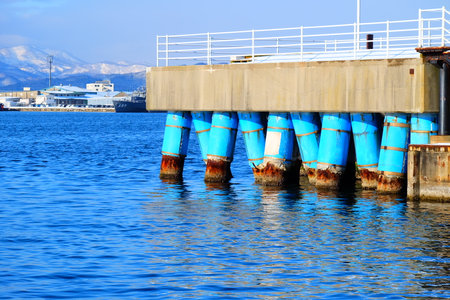 Old pier with blue buoys in the sea, Greece. Blue sky background.の写真素材