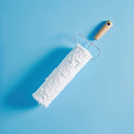 Paint roller with white paint on blue background. Top view.の素材