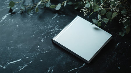 Blank notebook on black marble table with eucalyptus branchの素材