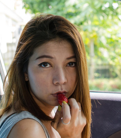 woman in nature is eating strawberryの写真素材
