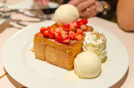 Ice-cream with bread and strawberry on white dishの写真素材