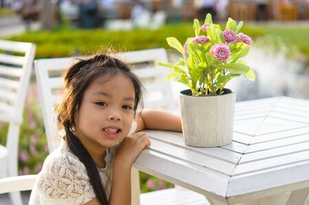 Girl sitting. Picture with flowers in a vase.の写真素材