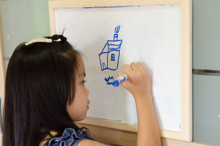 Child drawing on a white board at home.