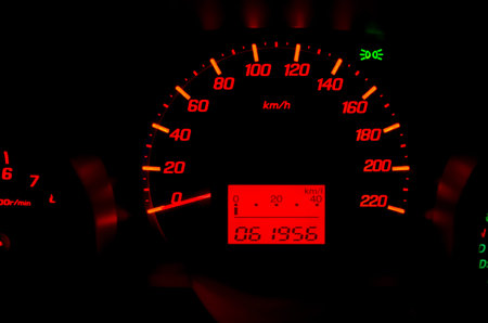 Close up of car dashboard with speed and rpm dials.