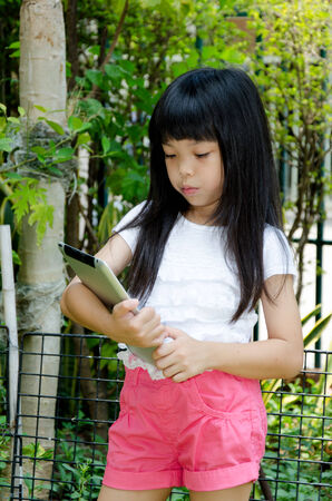 Kid playing tablet in the park .の写真素材